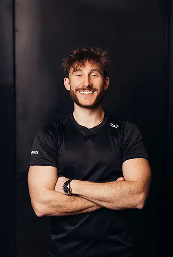 Homme coach bras croisés : Coach Atlas Gym – spécialiste en renforcement musculaire et performance.