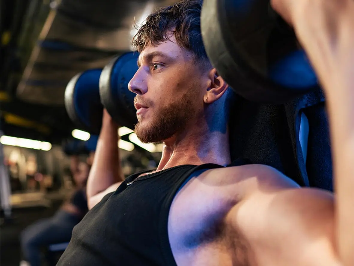 Athlète réalisant un curl haltère dans la salle musculation Atlas Gym