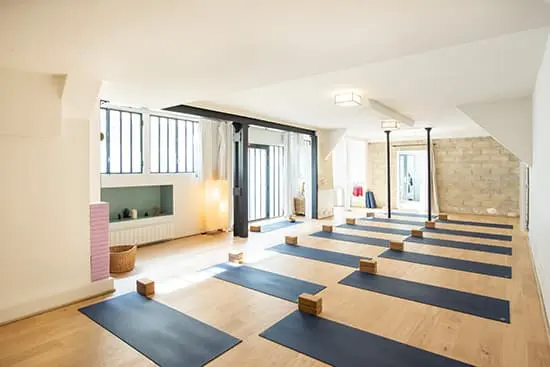 Salle de yoga lumineuse avec tatamis blancs et ambiance zen – Atlas Gym